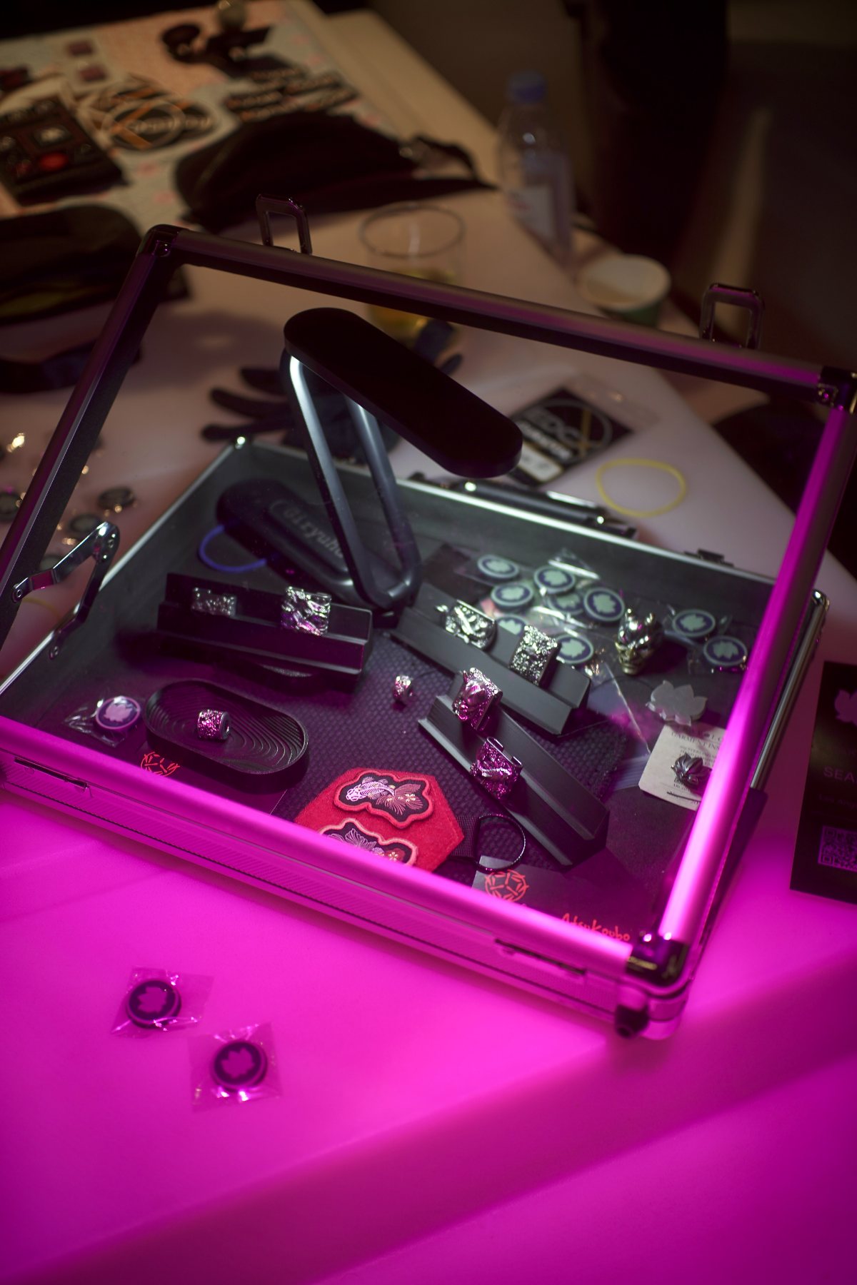 A glass display case of silver pieces under coloured light