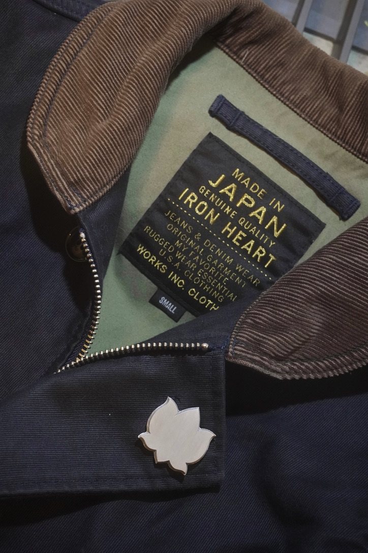 A lotus prototype worn on the placket of a dark jacket beside its maker's label