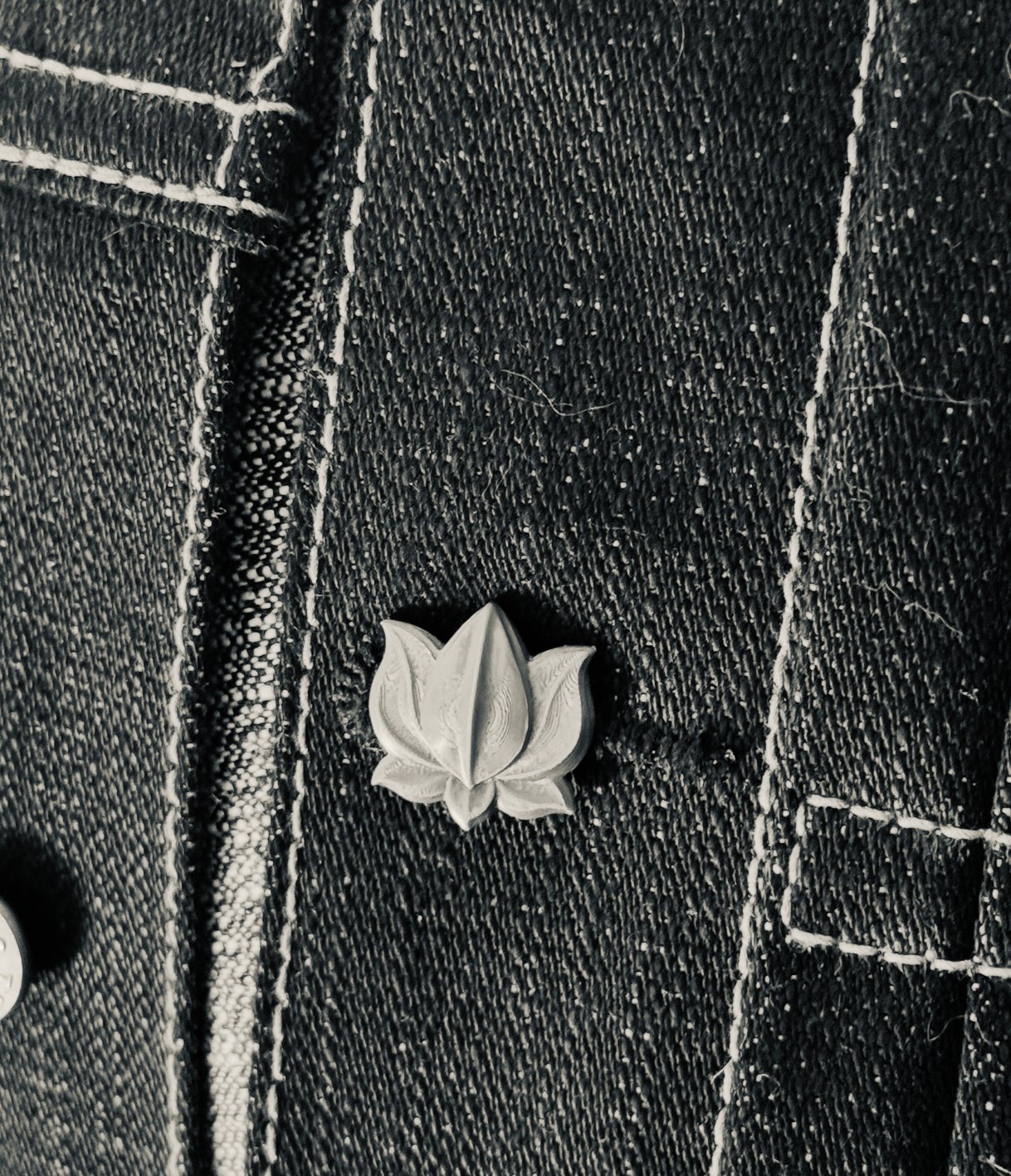 The final prototype, its lotus cut in dimensional relief, worn in the buttonhole of a black denim jacket