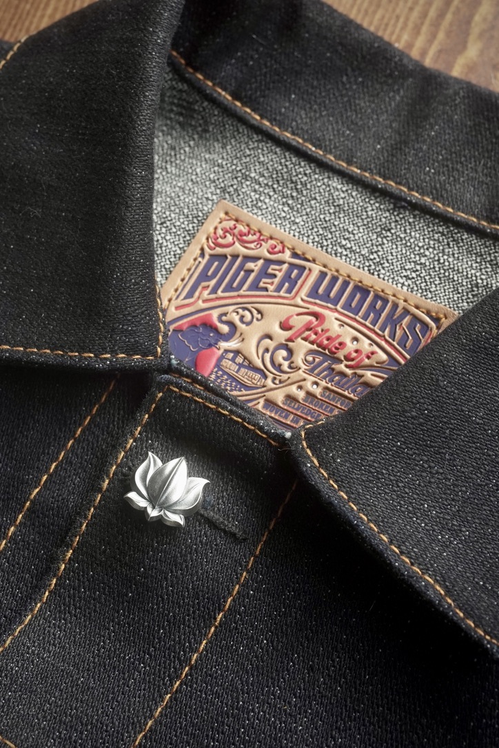 Lotus 001 in sterling silver mounted through the buttonhole of a black selvedge denim jacket